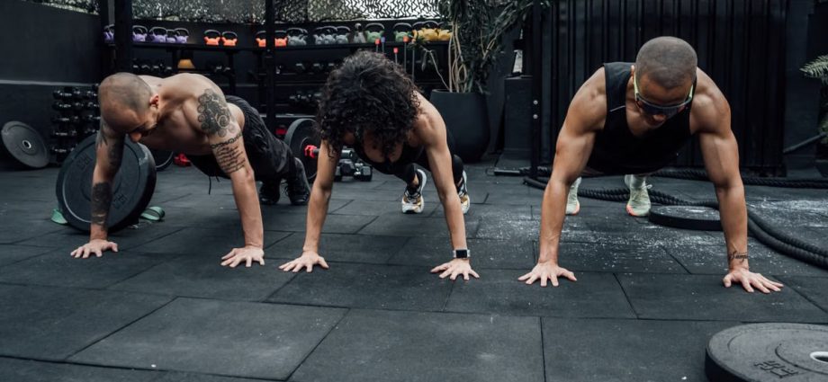 Three individuals performing push-ups together in a Mexico City gym setting.